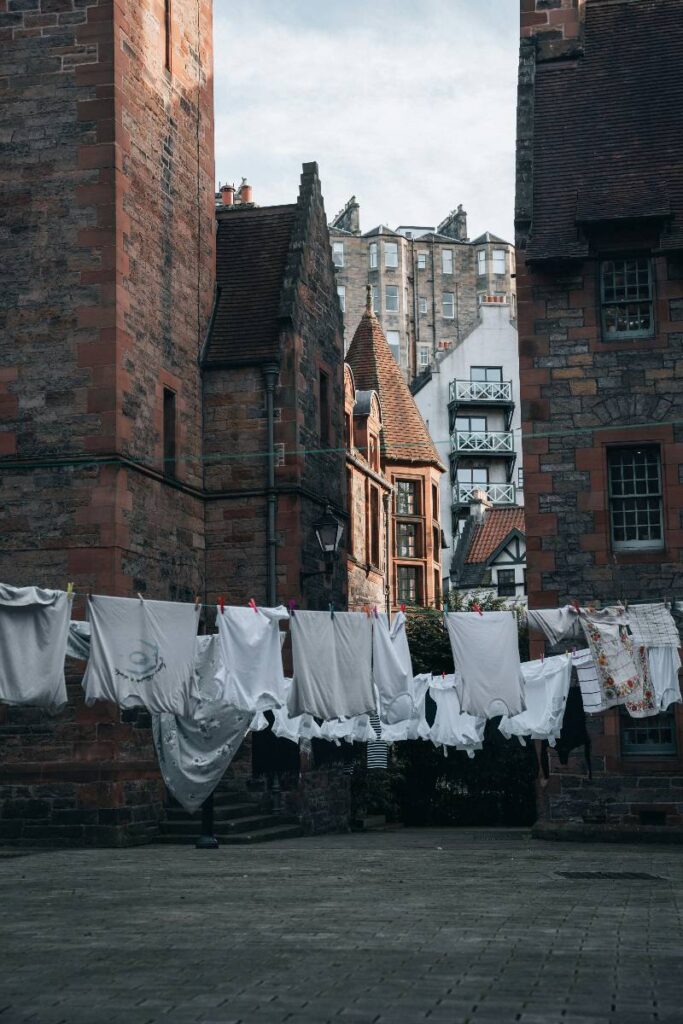 Clothes hanging on a line between old brick buildings in Dean Village, Edinburgh, with a mix of historic and modern architecture in the background