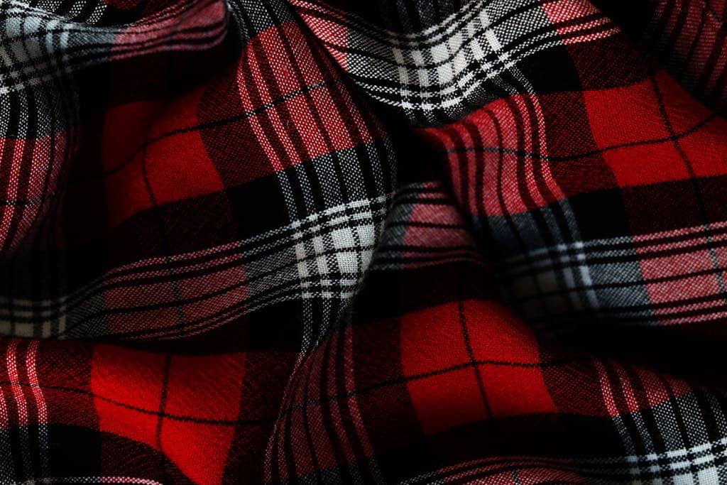 Detailed close-up of a vibrant red and black plaid fabric highlighting texture and pattern.